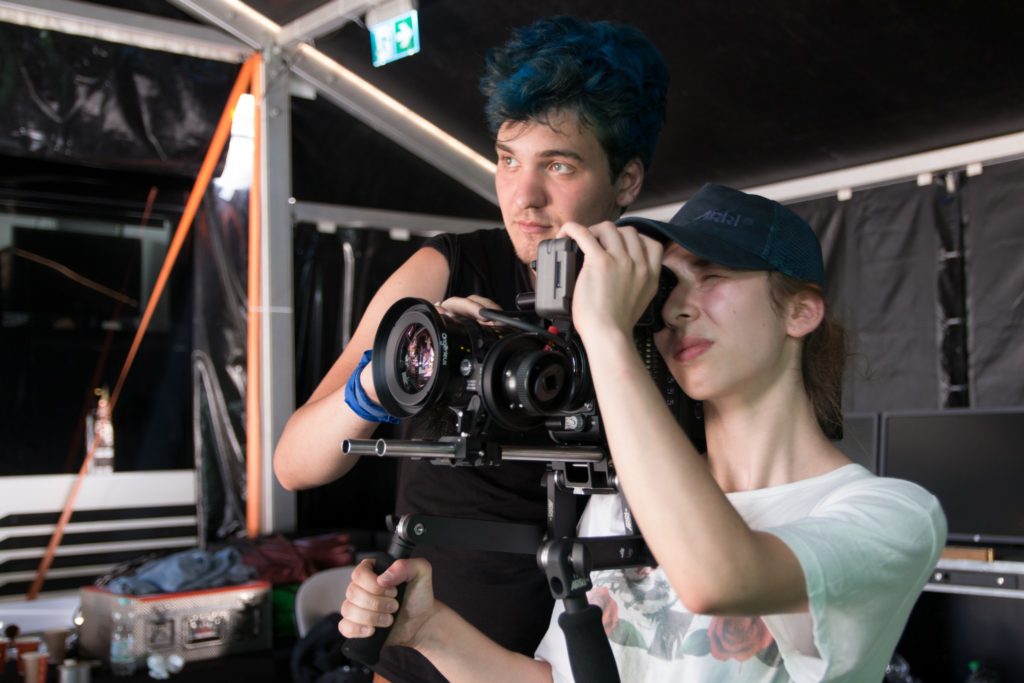 Dwójka młodych ludzi - uczestników kursu audiowizualnego obsługuje kamerę w namiocie Cinebusa